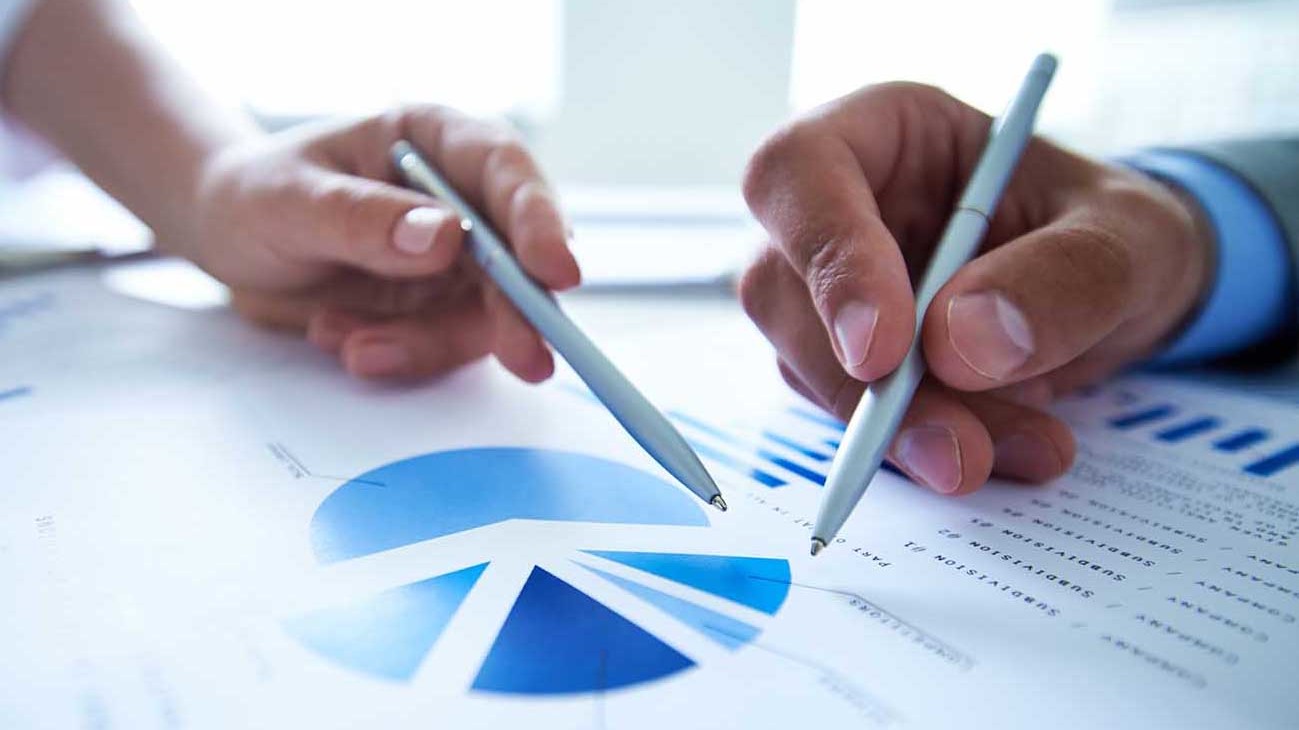 two hands holding pens referencing a graph